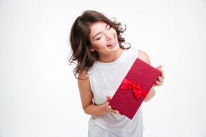 Portrait of a laughing woman holding gift box isolated on a white background
